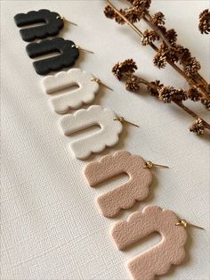 four pairs of earrings sitting on top of a white table next to dried flowers and branches