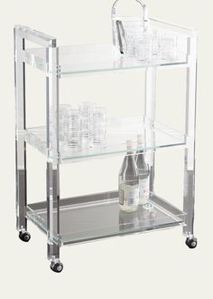 an acrylic shelf with bottles and glasses on wheels is shown against a white background