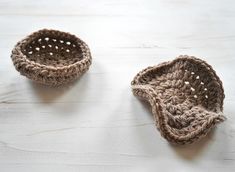 two small crocheted baskets sitting on top of a white wooden table next to each other