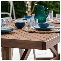 a wooden table topped with plates and bowls