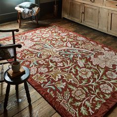 a living room area with a chair and rug on the floor, next to a dresser