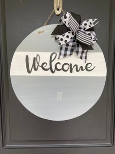 a welcome sign hanging on the front door of a house with black and white polka dot ribbon