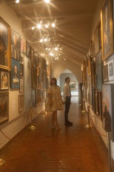 two people standing in an art gallery looking at pictures on the wall and holding hands