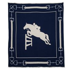 a blue and white blanket with a horse jumping over a hurdle on it's back