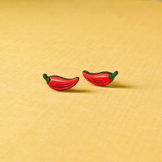 two small red chili peppers sitting on top of a yellow table next to each other