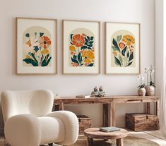 three framed art pieces hang on the wall above a white chair in a living room