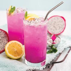 two glasses filled with pink lemonade and garnish next to sliced oranges