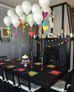 a table topped with lots of balloons next to a fire place