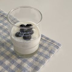 a glass filled with yogurt and blueberries on top of a checkered napkin