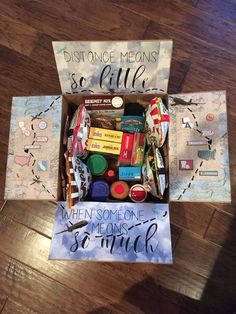 a box filled with assorted items sitting on top of a wooden floor next to a sign that says distance means so little