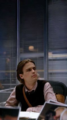 a young man sitting at a desk in an office