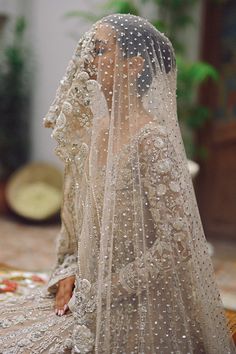 a woman wearing a wedding veil and sitting on the floor in front of a potted plant