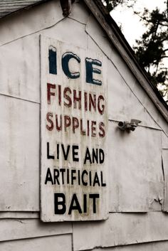 an old ice fishing supplies sign on the side of a building with trees in the background