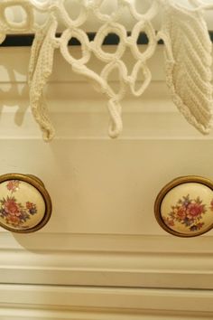 two knobs with flowers painted on them are hanging from a curtain rod in front of a window