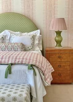 a bed sitting next to a nightstand with a lamp on top of it and a checkered bedspread