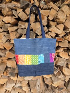 a multicolored tote bag sitting on top of a pile of firewood