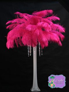 a tall pink feather tree with beads on it's base and a black background