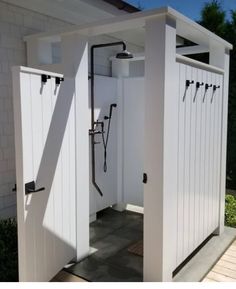 the inside of a white shed with black handles and hooks on it's doors