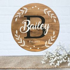 a wooden sign with the word bailey on it next to some flowers and a vase