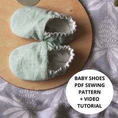 a pair of baby shoes sitting on top of a wooden plate next to a spoon