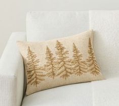 a white couch with a brown pine tree pillow on it's back and side