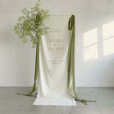 a white chair with a green ribbon tied around it and a bouquet of flowers on the back