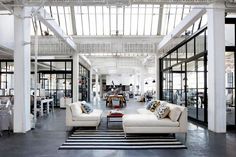 a large room with couches, tables and chairs inside of it on top of a black and white striped rug