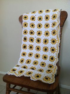 a crocheted blanket sitting on top of a wooden chair next to a wall