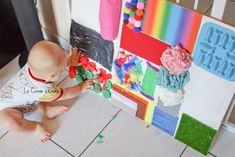 a small child playing with some toys in front of a wall made out of paper