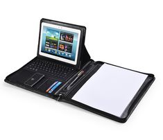 an open laptop computer sitting on top of a black leather case with a note pad and pen