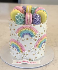 a decorated birthday cake with rainbow cookies and macaroons