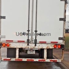 the back end of a white truck parked in a parking lot on a rainy day