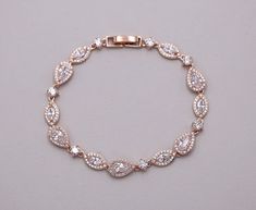 "Add bold elegance with these exquisitely designed open framed cubic zirconia teardrop wedding bracelet. Bracelet measures 7\" long. Matching (optional) necklace and earrings feature a pear top portion, a halo marquise piece ending in a double dangling tear drop pear accents set in brilliant rose gold. Matching necklace measures 16\" and is adjustable up to 18\" long. Available in silver, gold or rose gold finish. All jewelry features high quality electroplating that does not fade or chip and is Pear-shaped Silver Bracelet For Weddings, Elegant Pear-shaped Bracelets For Wedding, Elegant Pear-shaped Bracelet For Wedding, Gold Wedding Bracelet, Rose Gold Bracelet Set, Silver Wedding Bracelet, Rose Gold Jewelry Set, Gold Bracelet Wedding, Rose Gold Earrings Wedding