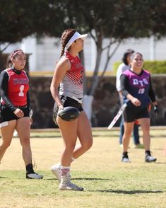 the girls are playing frisbee on the field in their sport uniforms and headbands