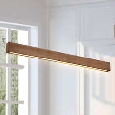 a wooden light hanging from the ceiling in a room with white walls and window sill