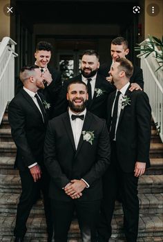 a group of men standing next to each other in front of a building with stairs