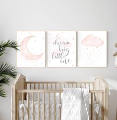 two pink and white nursery prints on the wall above a crib