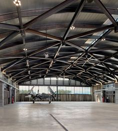 an airplane is parked in the middle of a large building with metal beams on it's ceiling