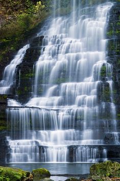 a large waterfall with lots of water cascading down it's sides in the woods