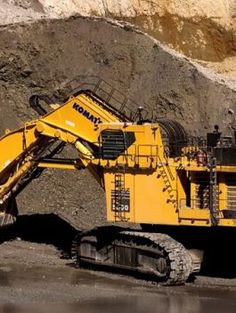 an excavator is parked in front of a pile of dirt and rocks