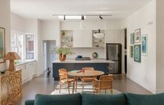 a kitchen and living room with white walls, wood flooring and blue couches