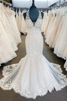 a white wedding dress on display in a bridal room with other dresses and gowns