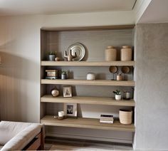 a living room filled with lots of shelves next to a wall mounted clock and lamp