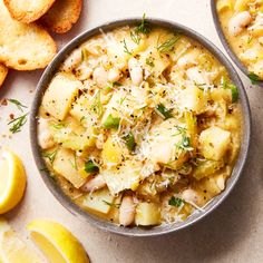 two bowls filled with food next to sliced lemons and crackers on a table