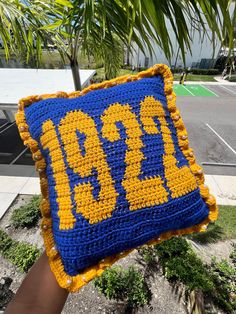 a crocheted blue and yellow pillow sitting on top of a tree