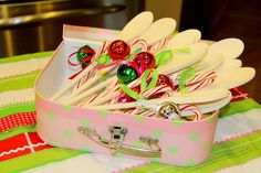 a pink suitcase filled with lots of candy canes and christmas decorations on top of a table