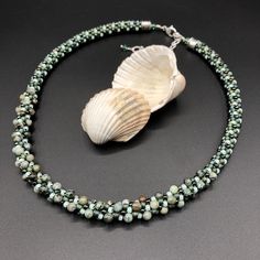 "This is an earthy, neutral necklace that will work with so many of your outfits. Warm forest green and contrasting seafoam green blend together with some beautiful semi-precious stones. The center segment features 4mm round African turquoise beads. Considered a stone of transformation and evolution, African turquoise (actually a form of jasper) is believed to awaken those who carry it to their highest spiritual purpose. The necklace measures 17 1/2\" long, and includes a 2 1/2\" extender, for a maximum length of 19\". Bali style sterling silver end caps give the finishing touch to this beautiful piece. The necklace is created using an ancient Japanese braiding technique called Kumihimo. A wooden stand called a marudai is used as a loom. Multiple cords are beaded with carefully selected co Artisan Green Jewelry With Tiny Beads, Adjustable Green Crystal Necklace, Green Multi-strand Hand-strung Beaded Necklaces, Adjustable Green Hand-strung Beaded Necklaces, Adjustable Green Necklaces With Faceted Beads, Adjustable Green Necklace With Faceted Beads, Artisan Green Necklace With Tiny Beads, Green Multi-strand Hand-strung Necklaces, Adjustable Unique Turquoise Necklace