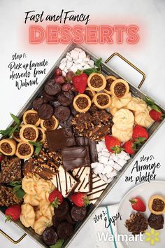 a tray filled with assorted desserts on top of a white table next to a bowl of strawberries