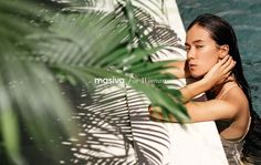 a woman leaning against a wall next to a palm tree