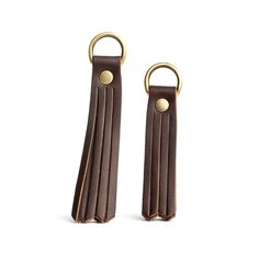 two brown leather key fobs with gold rings on each one and the other side